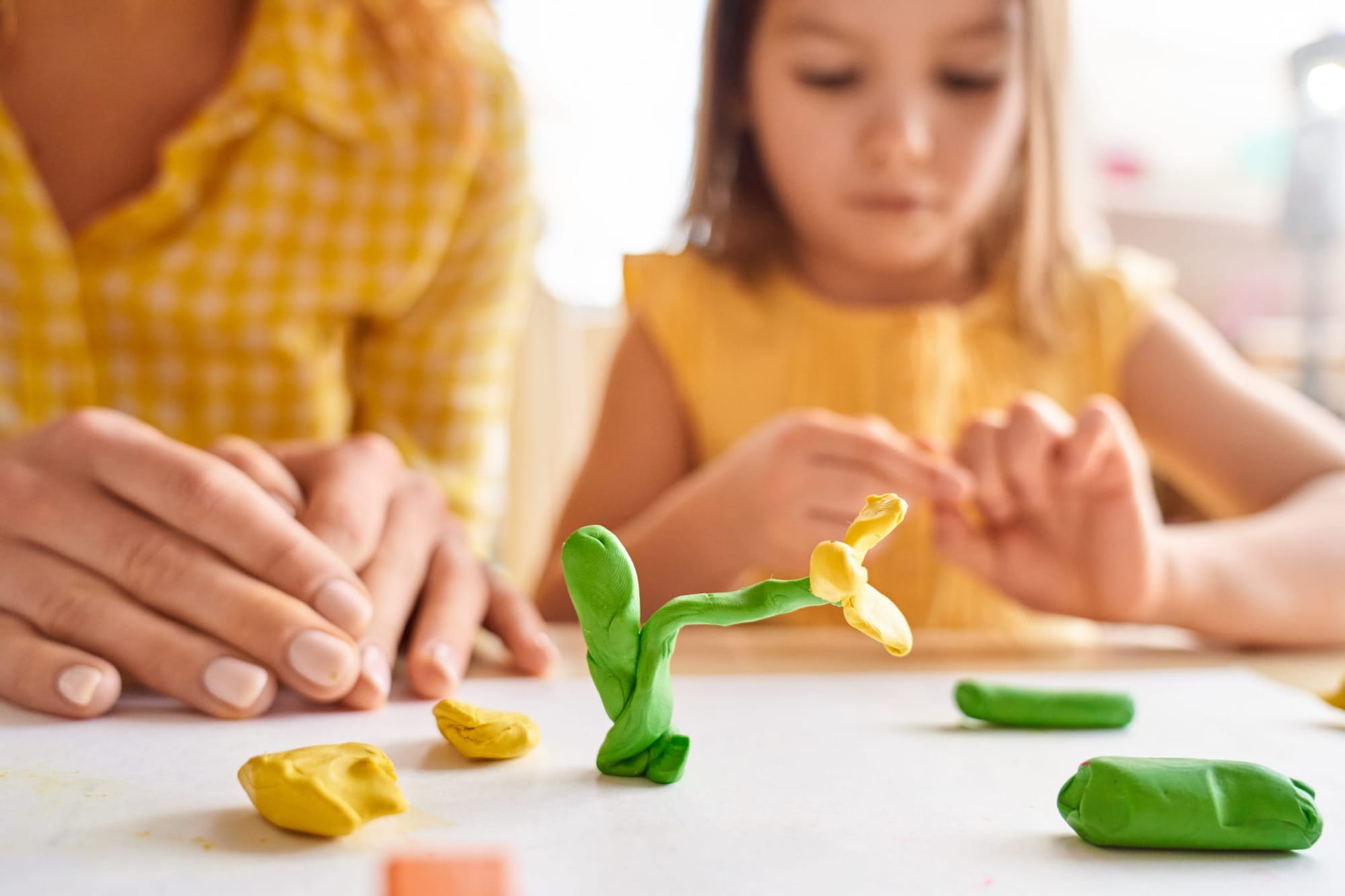 Mother and her young daughter playing with plasticine on a table