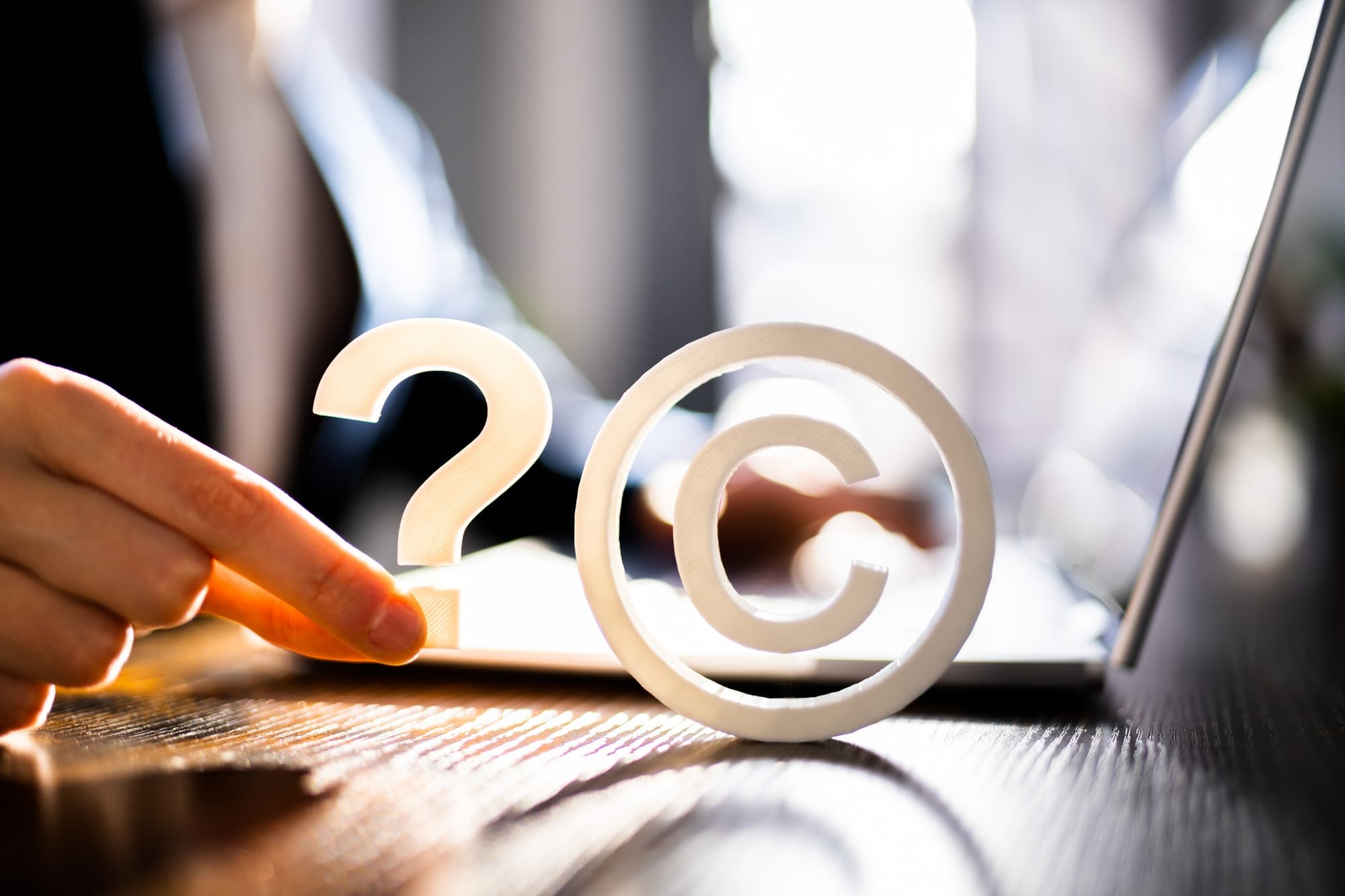 A man's hand and computer on a desk with the copyright logo and a question mark.
