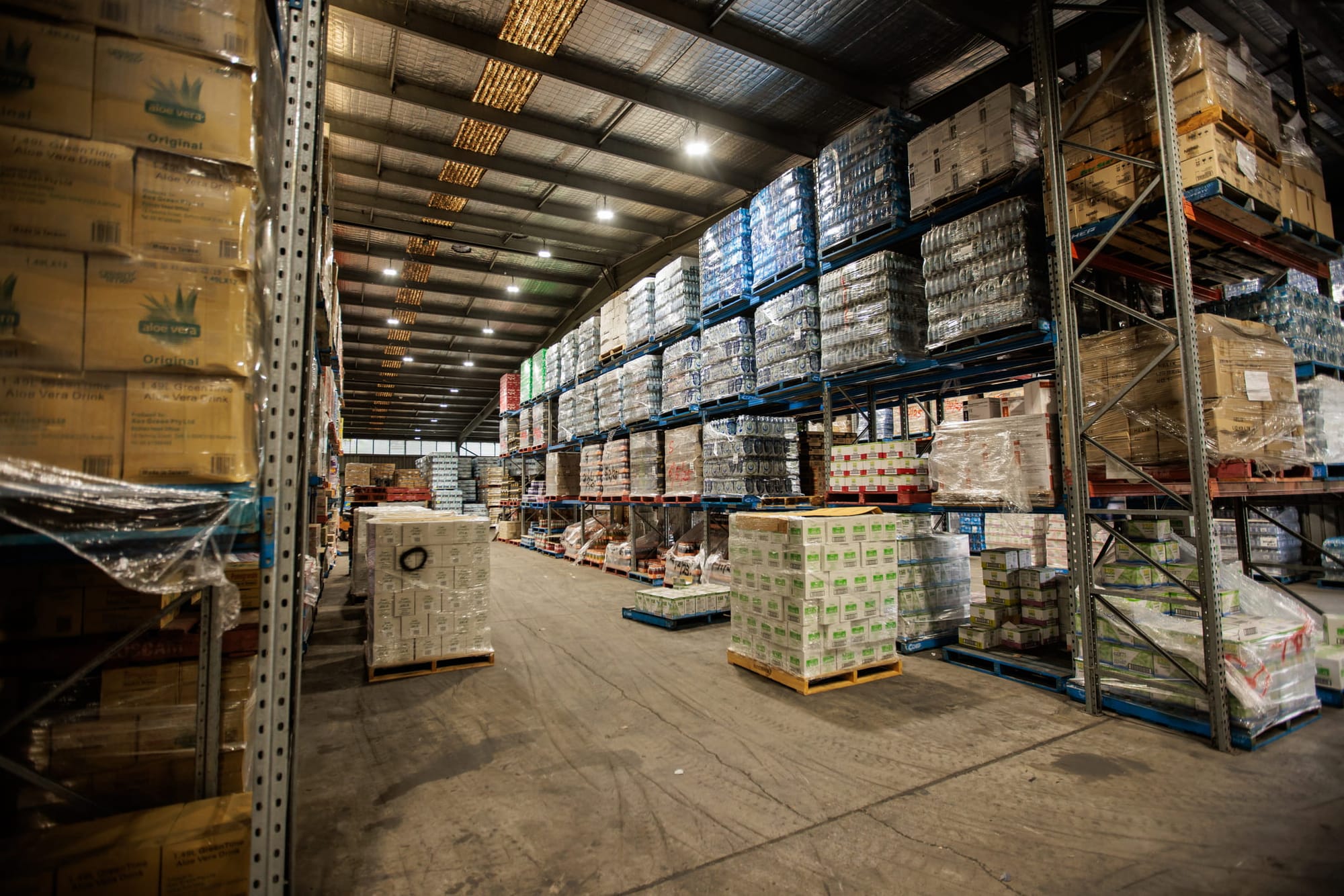Inside of a spacious warehouse with rows of racks filled with merchandise.