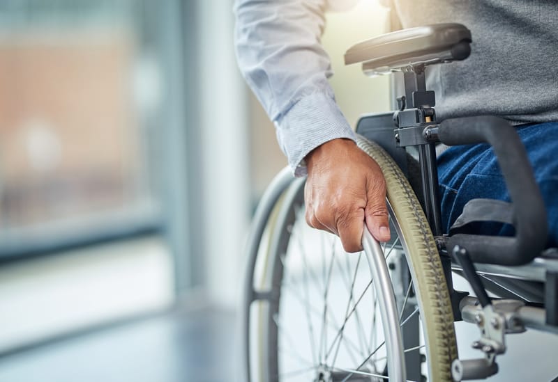 Close-up of a man's hand in a wheelchair, holding the wheel