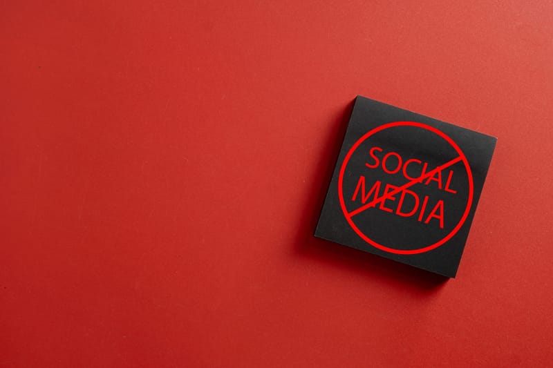 Black sticky note with crossed out social media text on red background