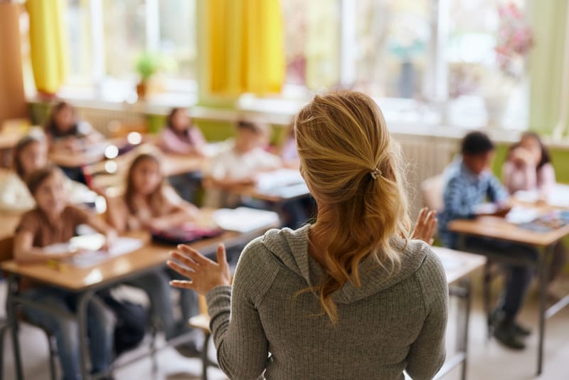 Rear view of a female teacher teaching her students during a class at primary school.