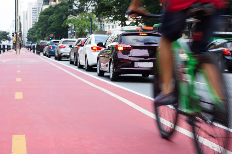 Cyclist in cycling lane, with bumper-to-bumper traffic beside them.